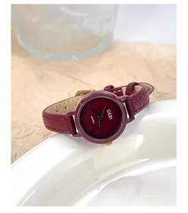 Detail of burgundy leather strap and round gold dial on a minimalist quartz watch