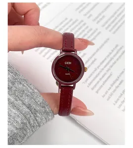 Close-up of a small vintage women quartz watch with a burgundy leather strap on book