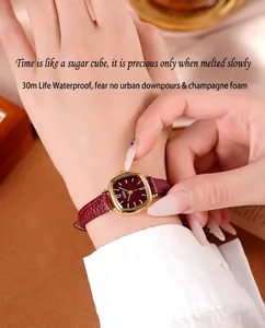Montre élégante en cuir bordeaux au poignet avec cadran doré et étanchéité à 30 mètres