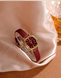 Gros plan d'une montre à quartz dorée carrée vintage avec bracelet et cadran rouge foncé