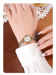 Gros plan d'une montre rectangulaire dorée minimaliste avec bracelet en cuir gris au poignet