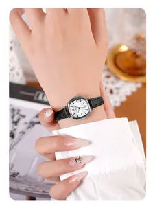 Gros plan d'une montre à quartz carrée en argent avec bracelet cuir noir sur un poignet