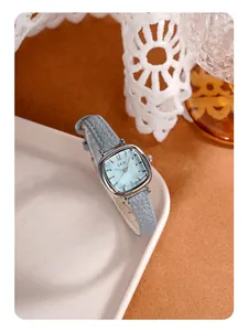 Détail d'un cadran bleu clair carré et boîtier argenté sur une montre en cuir