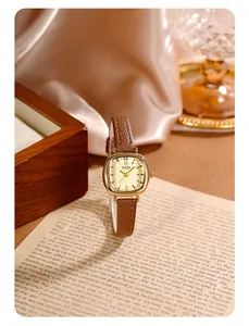 Gros plan d'une montre carrée vintage pour femme avec cadran doré et bracelet en cuir