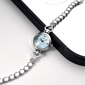Macro shot of silver metal watch band with hollow heart links and sparkling rhinestones
