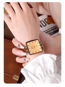 Détail de la montre carrée Gedi dorée avec bracelet à maillons sur un poignet