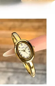Detalle del mini reloj ovalado dorado con números romanos usado en la punta del dedo