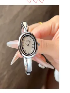 Detalle de reloj de pulsera ovalado plateado con números romanos y acero inoxidable