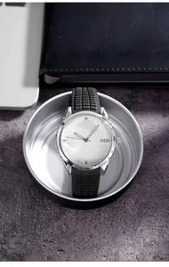 Macro shot of silver dial with radial texture and black silicone strap on office desk