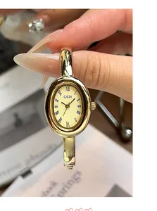 Vista macro de un reloj de mujer ovalado dorado con números romanos y acabado pulido