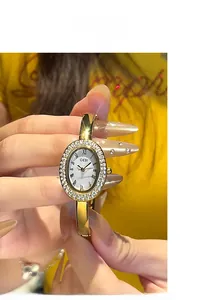 Makroaufnahme der goldenen Armreif-Uhr mit Kristalllünette und römischen Ziffern