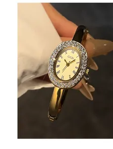 Details einer eleganten goldenen Armreif-Uhr mit Diamant-Lünette und römischen Ziffern