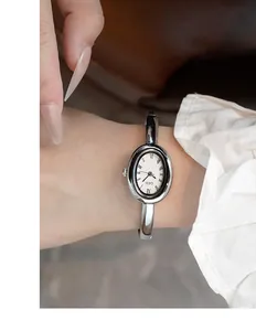 Detalle del reloj GEDI plateado ovalado con números romanos y pulsera de metal