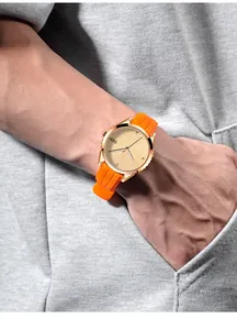 Detail of GEDI quartz watch with gold textured dial and bright orange silicone strap