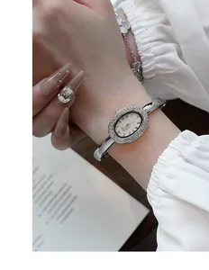 Nahaufnahme der silbernen ovalen Armreif-Uhr mit Diamantlünette und römischen Ziffern