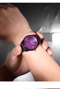 Close-up of purple dial quartz watch with black silicone strap worn on a female wrist