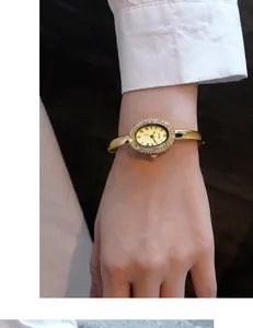 Detail der GEDI goldene Oval-Uhr mit Kristall-Lünette und römischen Ziffern am Handgelenk