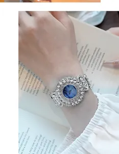 Detailopname van een horloge met blauwe sterrenwijzerplaat en strass-bezel om de pols