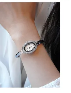 Detailansicht der silbernen ovalen Uhr mit Strasssteinen und römischen Ziffern am Handgelenk