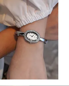 Details der silbernen ovalen Uhr mit Strass-Lünette und Metallarmband für Damen