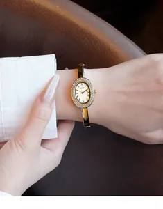 Nahaufnahme der GEDI ovalen Armreif-Uhr in Gold mit Kristall-Lünette am Handgelenk
