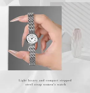 Detail of silver steel watch band and round white dial with Roman numerals