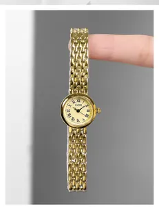 Macro view showing the delicate small gold watch dial with Roman numerals and metal strap