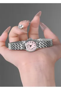 Close-up of elegant small pink dial watch with silver stainless steel link strap on wrist