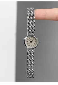 Detail view of dainty silver steel watch featuring Roman numerals and woven mesh bracelet