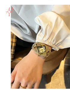 Détail d'une montre à quartz carrée dorée sertie de strass avec index en chiffres romains