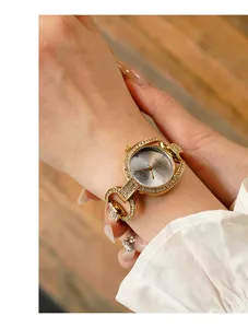 Close-up of luxury women's watch featuring rhinestone bezel and geometric gold strap