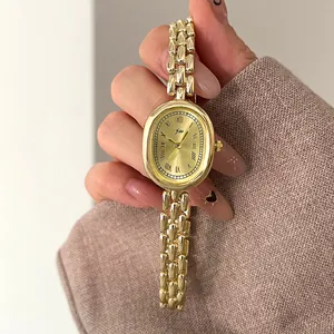 Close-up of golden oval vintage quartz watch with Roman numerals and elegant link bracelet