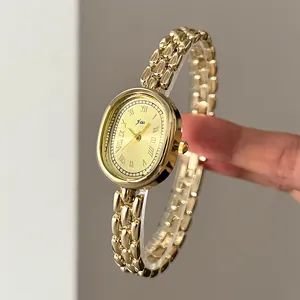 Detail view of oval gold quartz watch featuring Roman numerals and a triple link chain