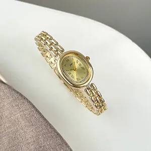 Close-up of vintage champagne gold oval watch face with Roman numerals and chain strap