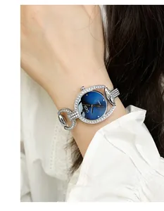 Close-up of a silver rhinestone watch with a gradient blue dial on a woman's wrist