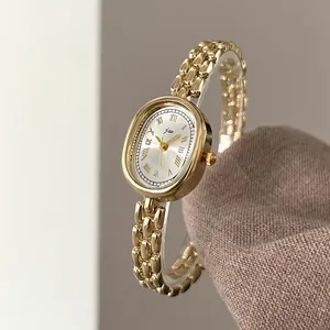 Macro shot of oval gold alloy watch dial with Roman numerals and chain strap texture