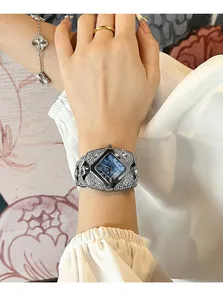 Gros plan d'une montre bracelet sertie de diamants avec cadran bleu foncé au poignet