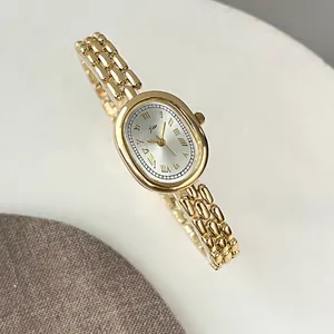 Macro detail of oval gold-tone watch with Roman numerals and elegant link bracelet