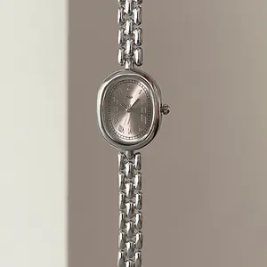 Detail of oval vintage silver watch with roman numerals and metallic chain bracelet