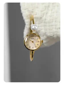 Dettaglio macro dell'orologio a bracciale GEDI dorato con perla e quadrante in madreperla