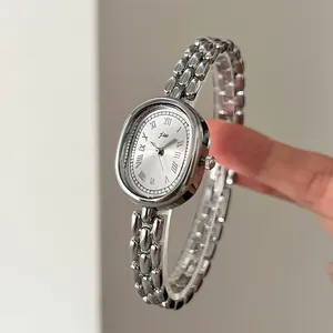 Detail of silver oval vintage watch with Roman numerals and elegant metal chain strap