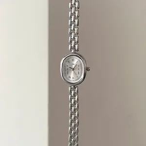 Detail of silver oval vintage watch featuring Roman numerals and chain strap bracelet