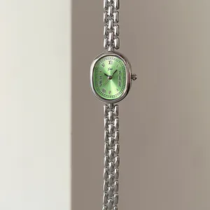 Detail of vintage oval green dial watch with Roman numerals and silver link bracelet