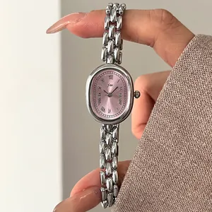 Close-up of vintage oval silver watch with pink dial and Roman numerals on chain bracelet