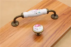 Detail of floral ceramic drawer handle with antique bronze base on a wood panel