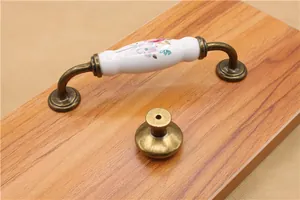 Close-up of vintage bronze and floral ceramic drawer handles on wooden background