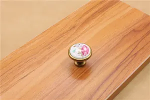 Detail of round ceramic cabinet knob with pink roses and vintage bronze metal base
