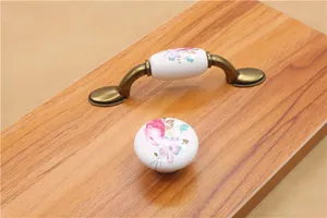 Close-up of vintage ceramic floral handles with bronze metal base on a wooden surface