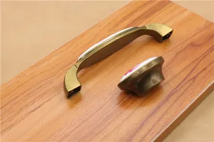 Floral ceramic cabinet handles with bronze alloy base on light wood background
