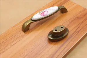 Detail of vintage ceramic pull handle with bronze metal and floral pattern for drawers